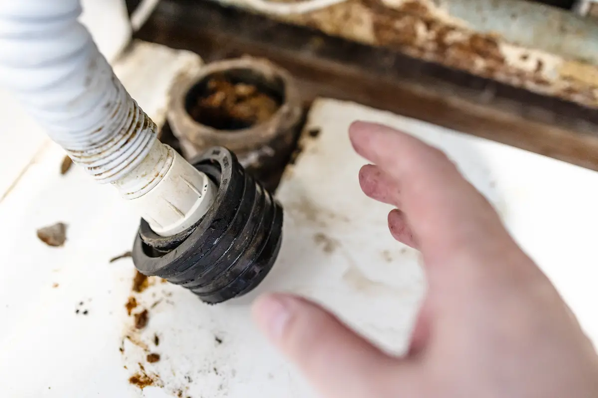 Hand of plumber near corrugated drain hose, drain cleaning